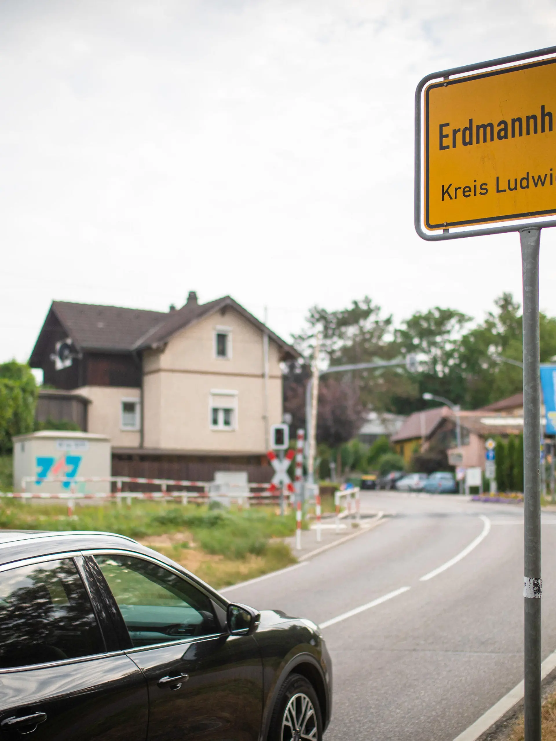 29.06.2023, Baden-Württemberg, Erdmannhausen: Ein Auto fährt am Ortseingangsschild von Erdmannhausen vorbei. Unter anderem für das übermäßig laute Schließen von Autotüren und das unnötige Laufenlassen von Motoren kann es in der baden-württembergischen Gemeinde Erdmannhausen bald Bußgelder geben. Foto: Christoph Schmidt/dpa +++ dpa-Bildfunk +++