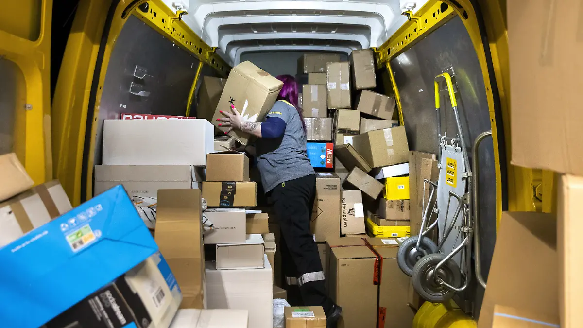Das Innere eines Paketautos mit vielen Paketen und einer Person.