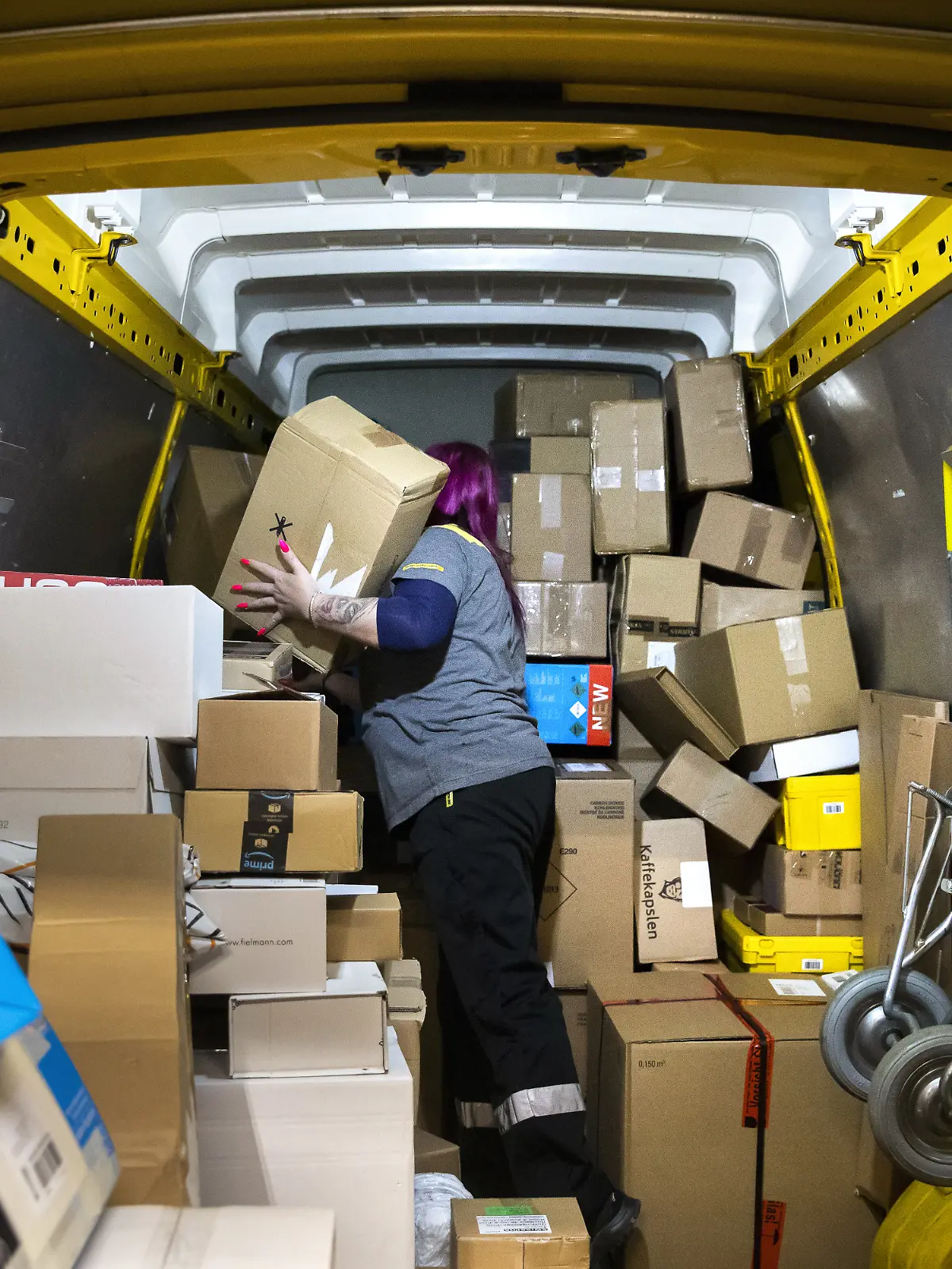 Das Innere eines Paketautos mit vielen Paketen und einer Person. 