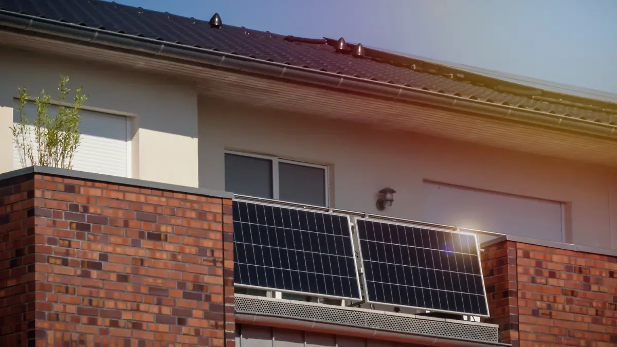 Balkonkraftwerke an einem Haus, welches von der Sonne angestrahlt wird.