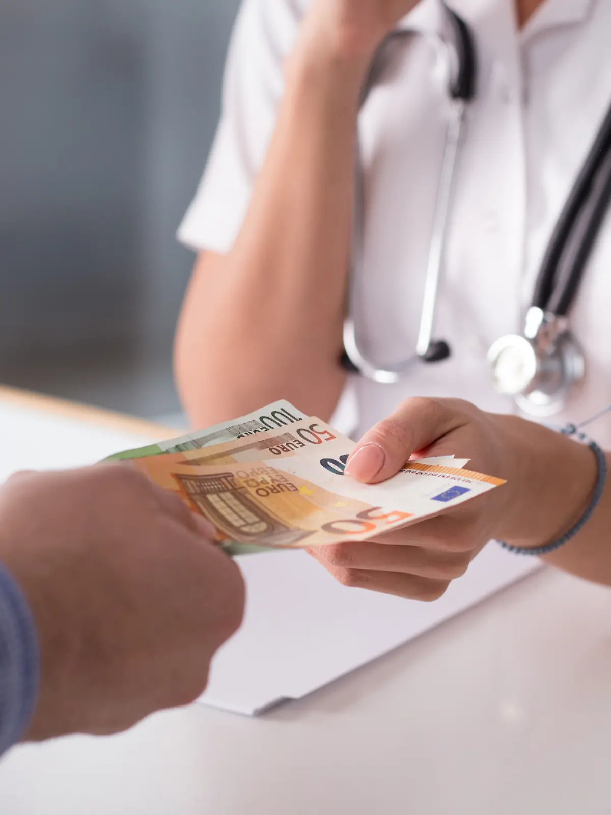 Mann zahlt Geld beim Arzt. 
