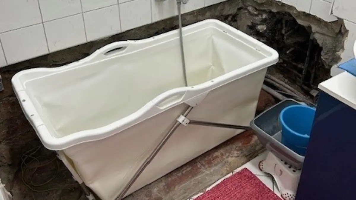 Das Badezimmer der Hüblers mit Campingbadewanne und riesigen Löchern in der Wand. 