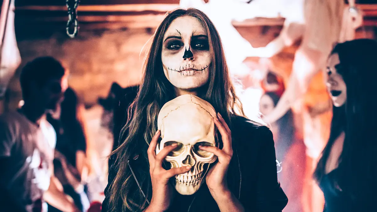 Frau mit Halloween-Verkleidung und Schädel in der Hand
