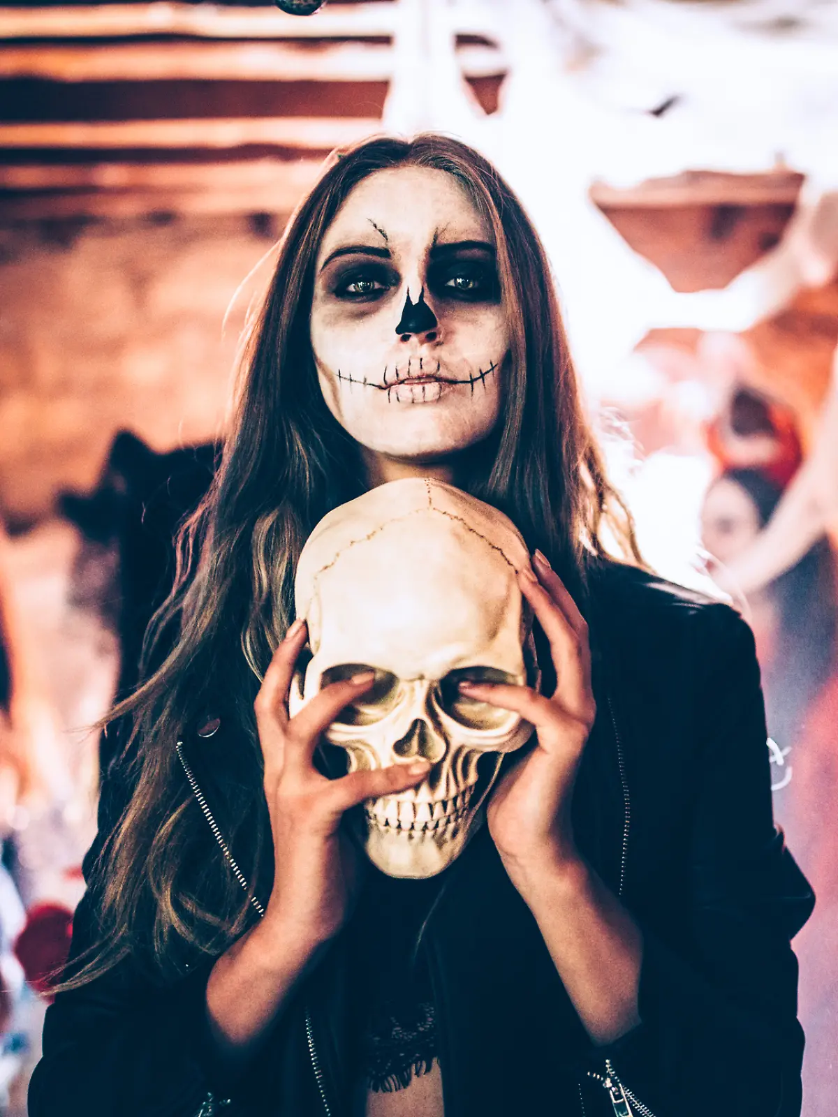 Frau mit Halloween-Verkleidung und Schädel in der Hand
