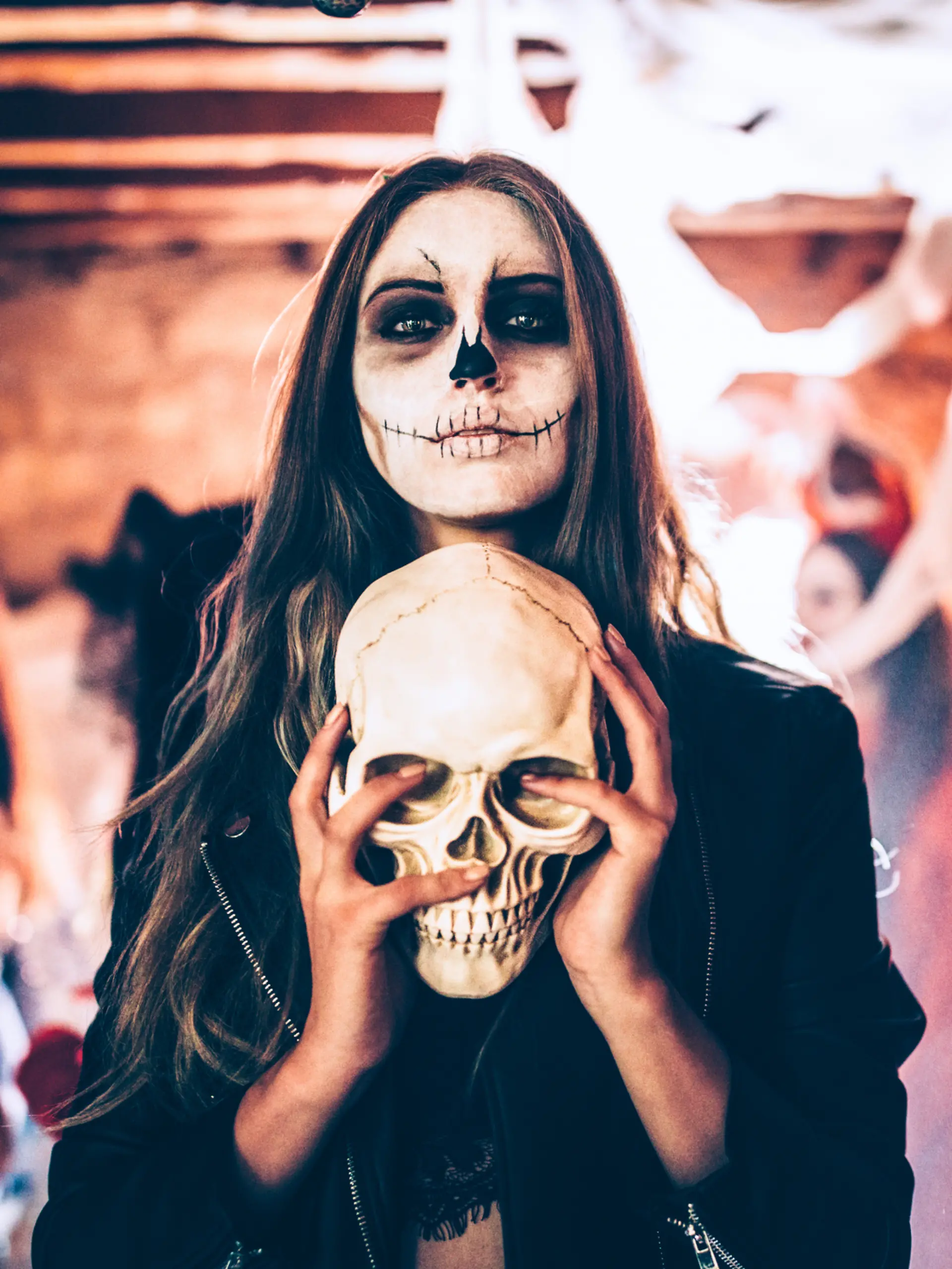 Frau mit Halloween-Verkleidung und Schädel in der Hand