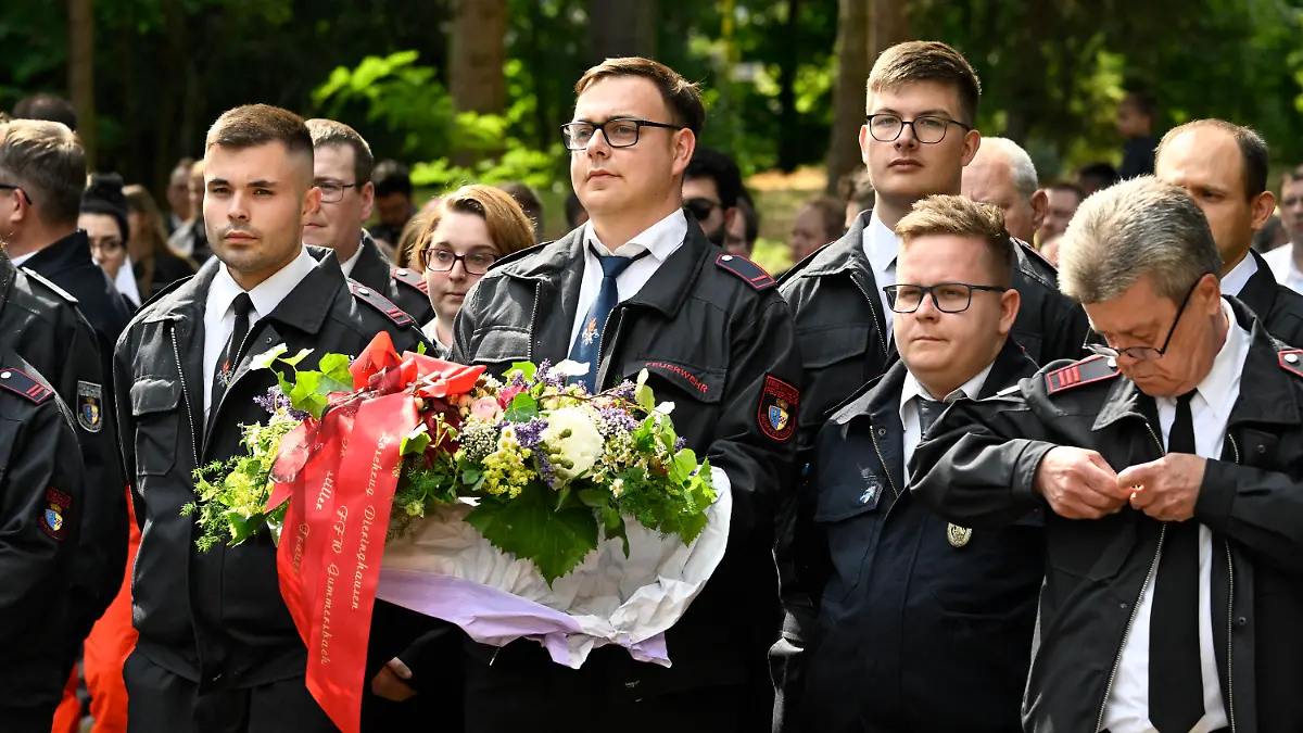 30.06.2023, Nordrhein-Westfalen, Sankt Augustin: Mit Blumen verabschieden verabschieden Feuerwehrleute aus ganz Deutschland bei der Trauerfeier ihre verstorbenen Kameraden. Die Stadt Sankt Augustin gedenkt der beiden im Einsatz verstorbenen Feuerwehrleute. Knapp zwei Wochen nach dem verheerenden Brand mit zwei toten Feuerwehrleuten in Sankt Augustin bei Bonn gibt es am Freitag dort eine öffentliche Trauerfeier. Foto: Roberto Pfeil/dpa +++ dpa-Bildfunk +++