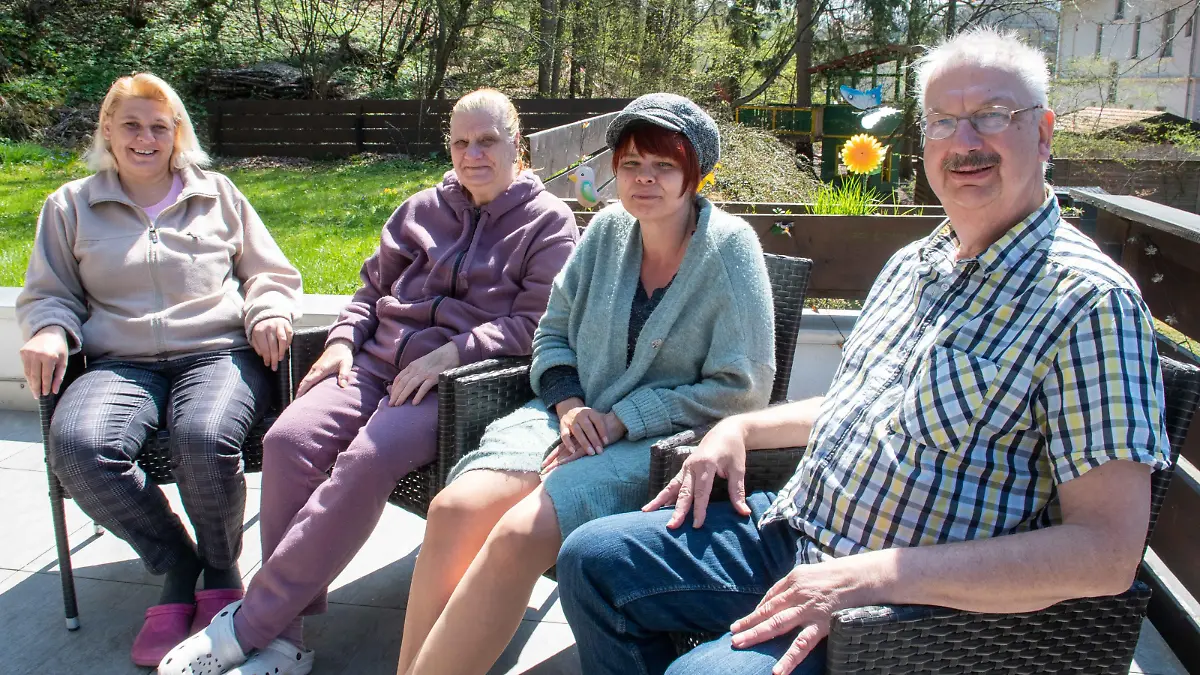 Ehepaar sitzt mit den aufgenommenen Flüchtlingen im Garten.