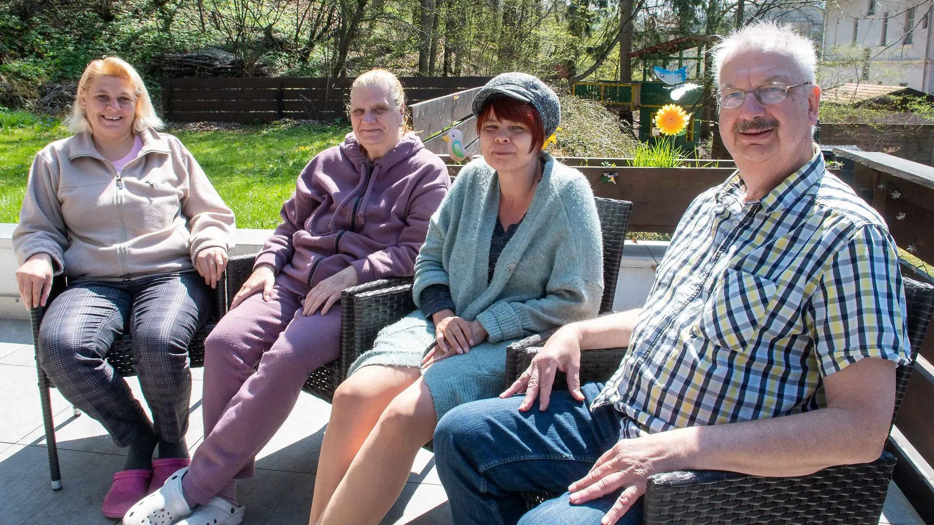 Ehepaar sitzt mit den aufgenommenen Flüchtlingen im Garten.