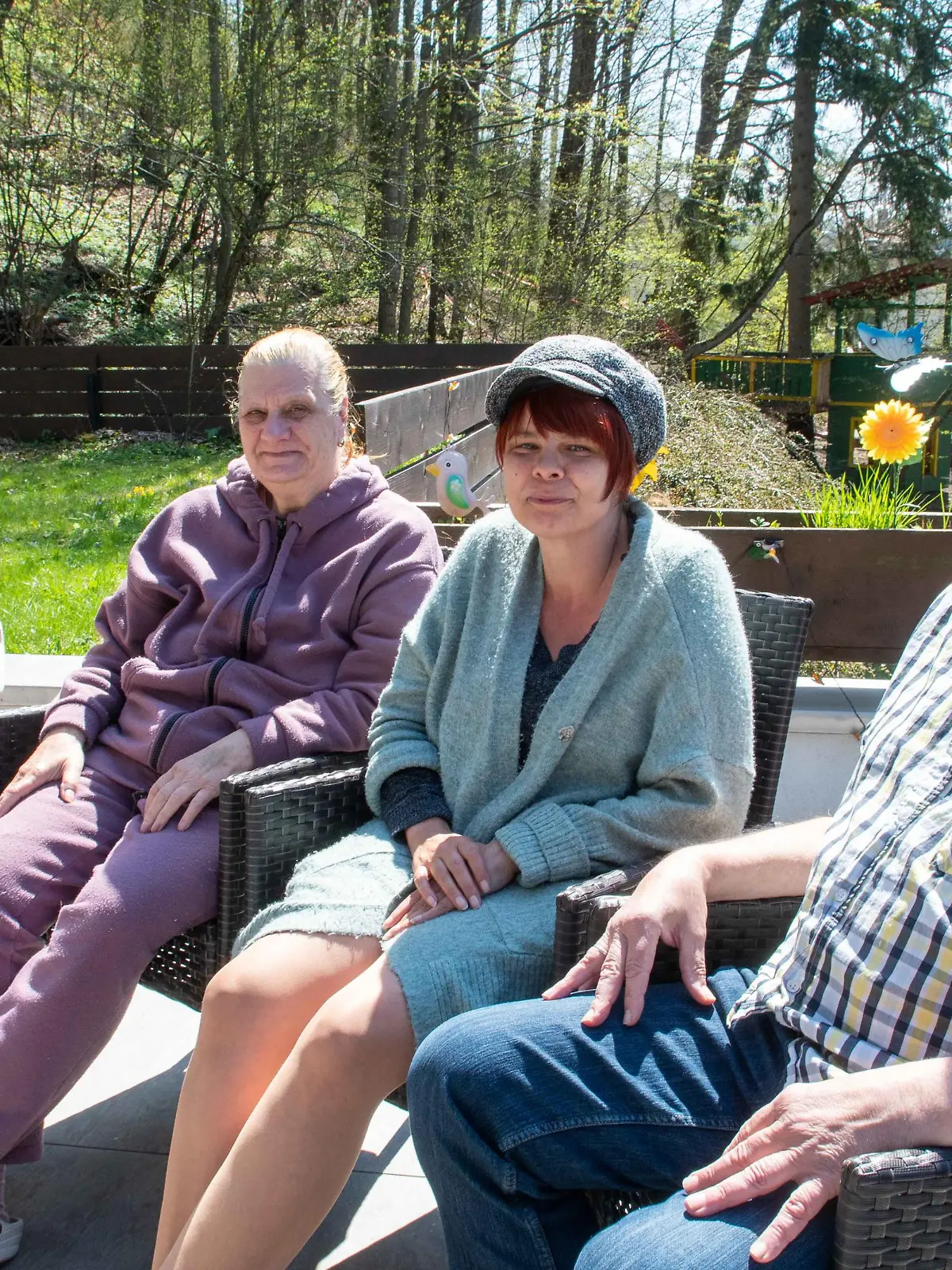 Ehepaar sitzt mit den aufgenommenen Flüchtlingen im Garten.