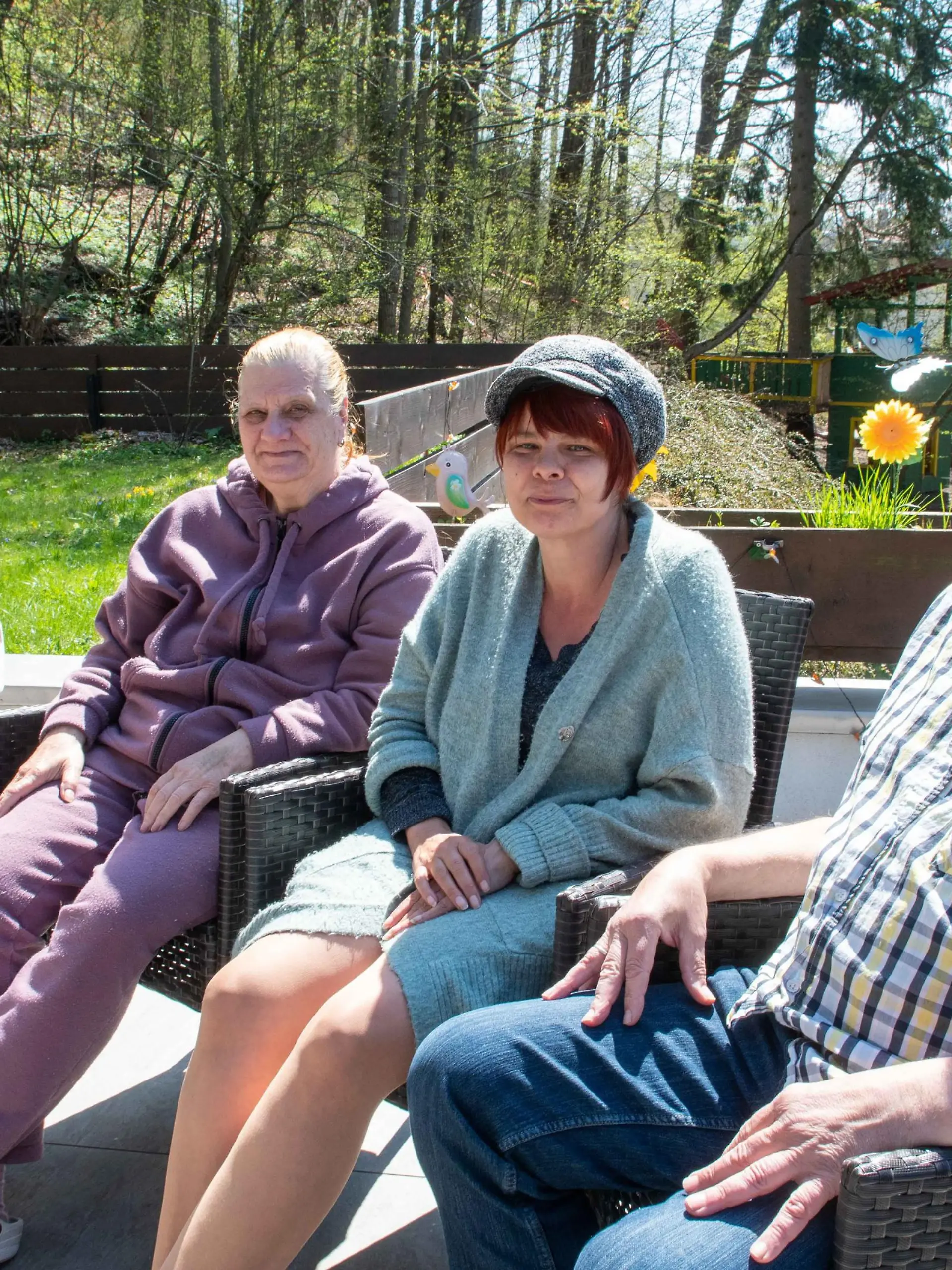 Ehepaar sitzt mit den aufgenommenen Flüchtlingen im Garten.