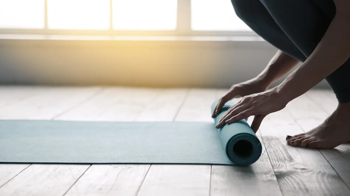 Frau rollt Sportmatte aus.