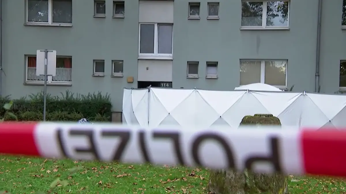 Eine Polizeiabsperrung vor einem Mehrfamilienhaus.