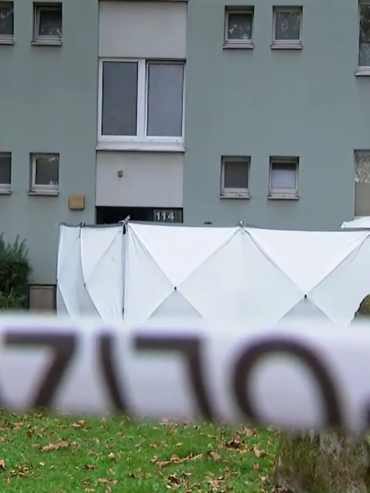 Eine Polizeiabsperrung vor einem Mehrfamilienhaus.