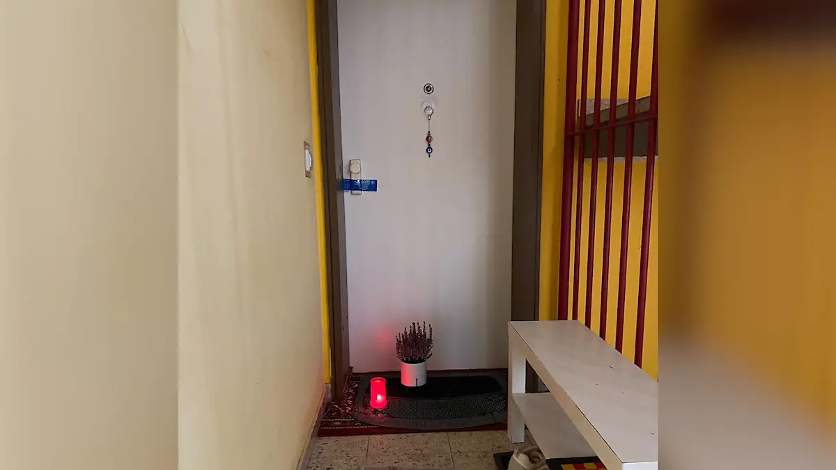 Eine Wohnungstür, davor eine Kerze. Das Schloss der Tür ist von der Polizei versiegelt worden.