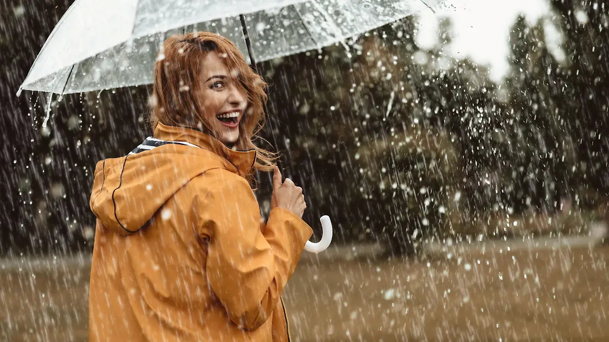 Frau mit Regenjacke und Regenschirm bei Regen