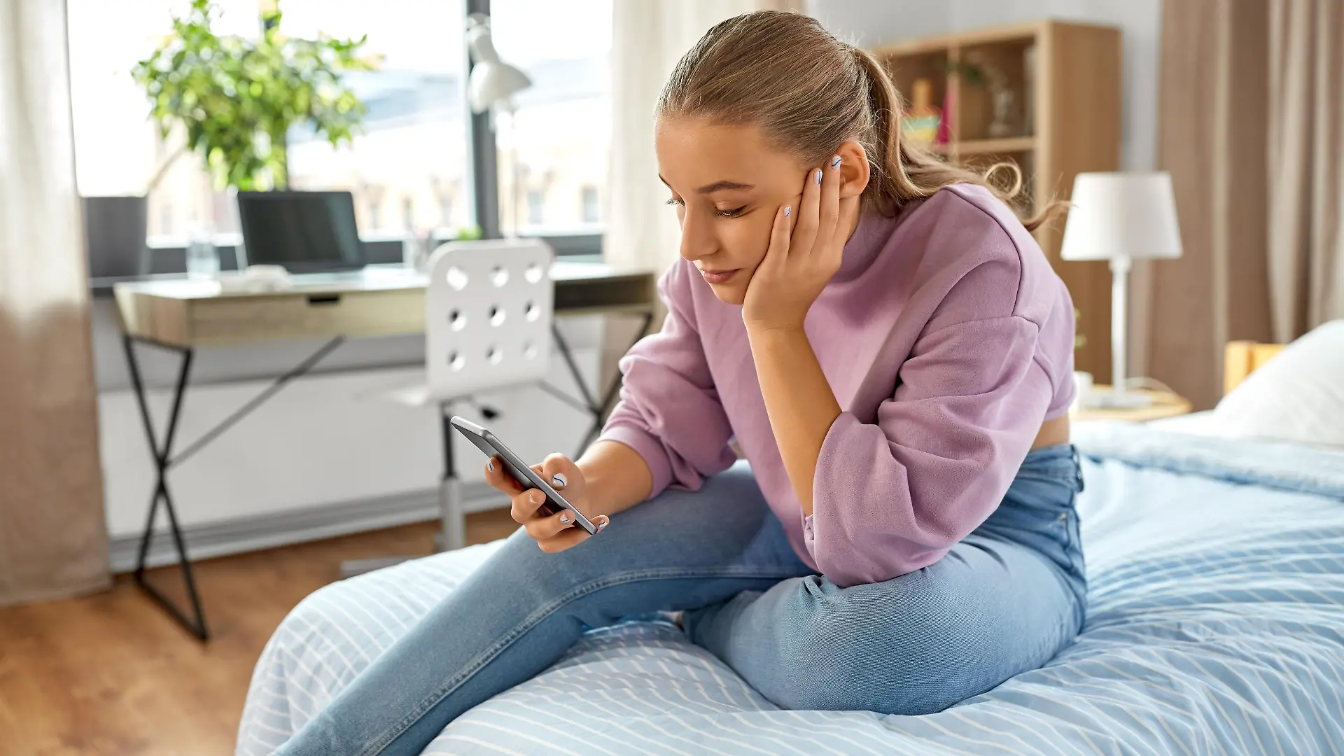 children, technology and communication concept - sad teenage girl with smartphone sitting on bed at home || Modellfreigabe vorhanden