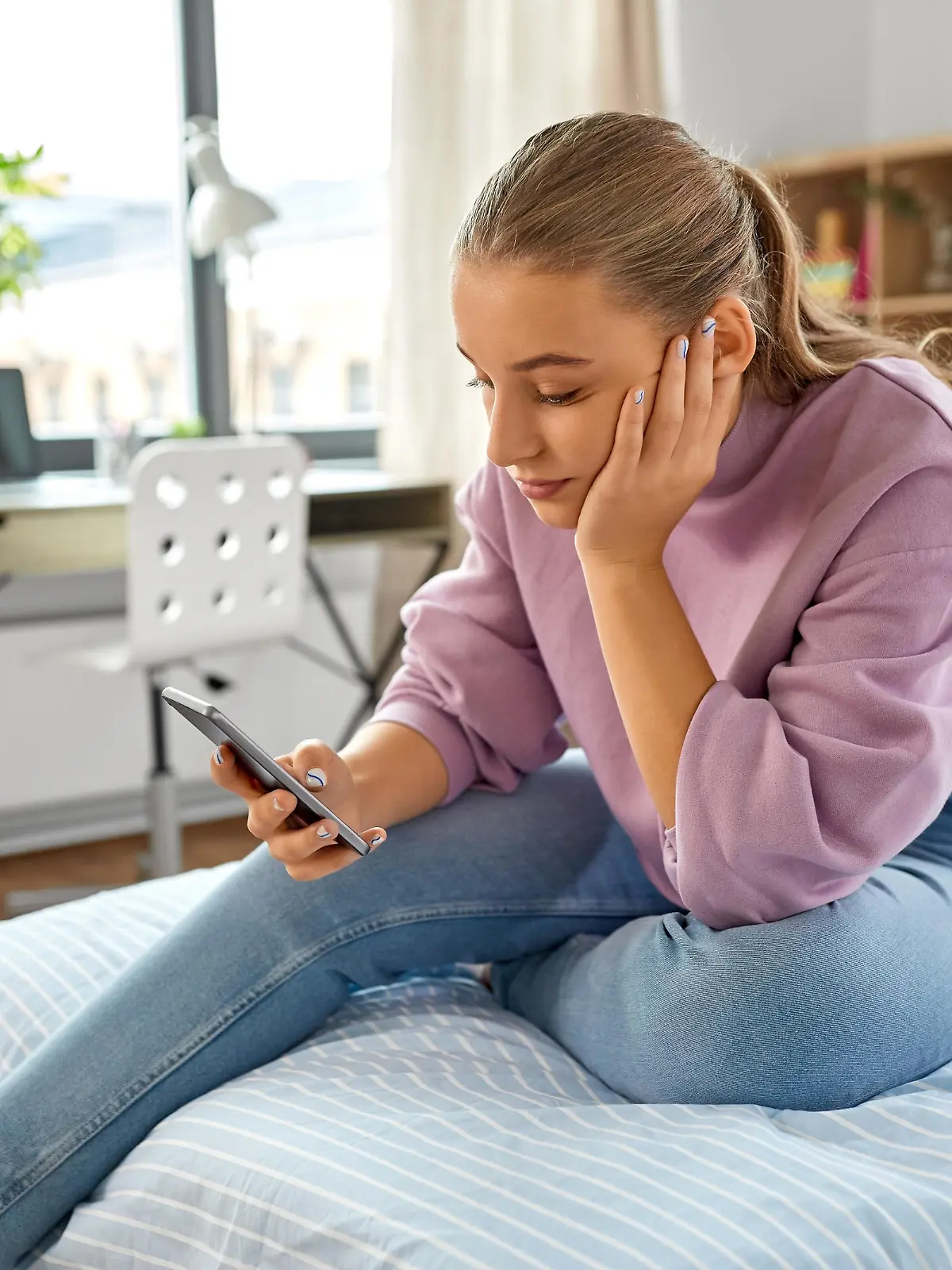 children, technology and communication concept - sad teenage girl with smartphone sitting on bed at home || Modellfreigabe vorhanden