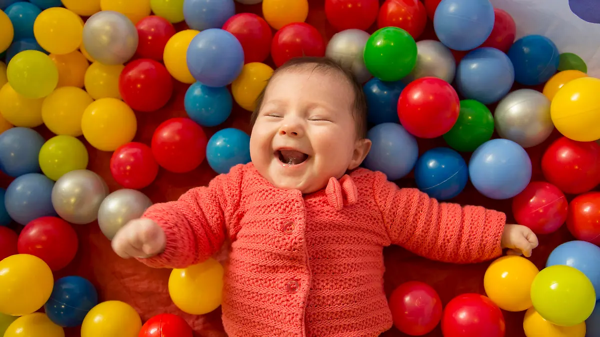 baby girl laughing in a sensory ball pit