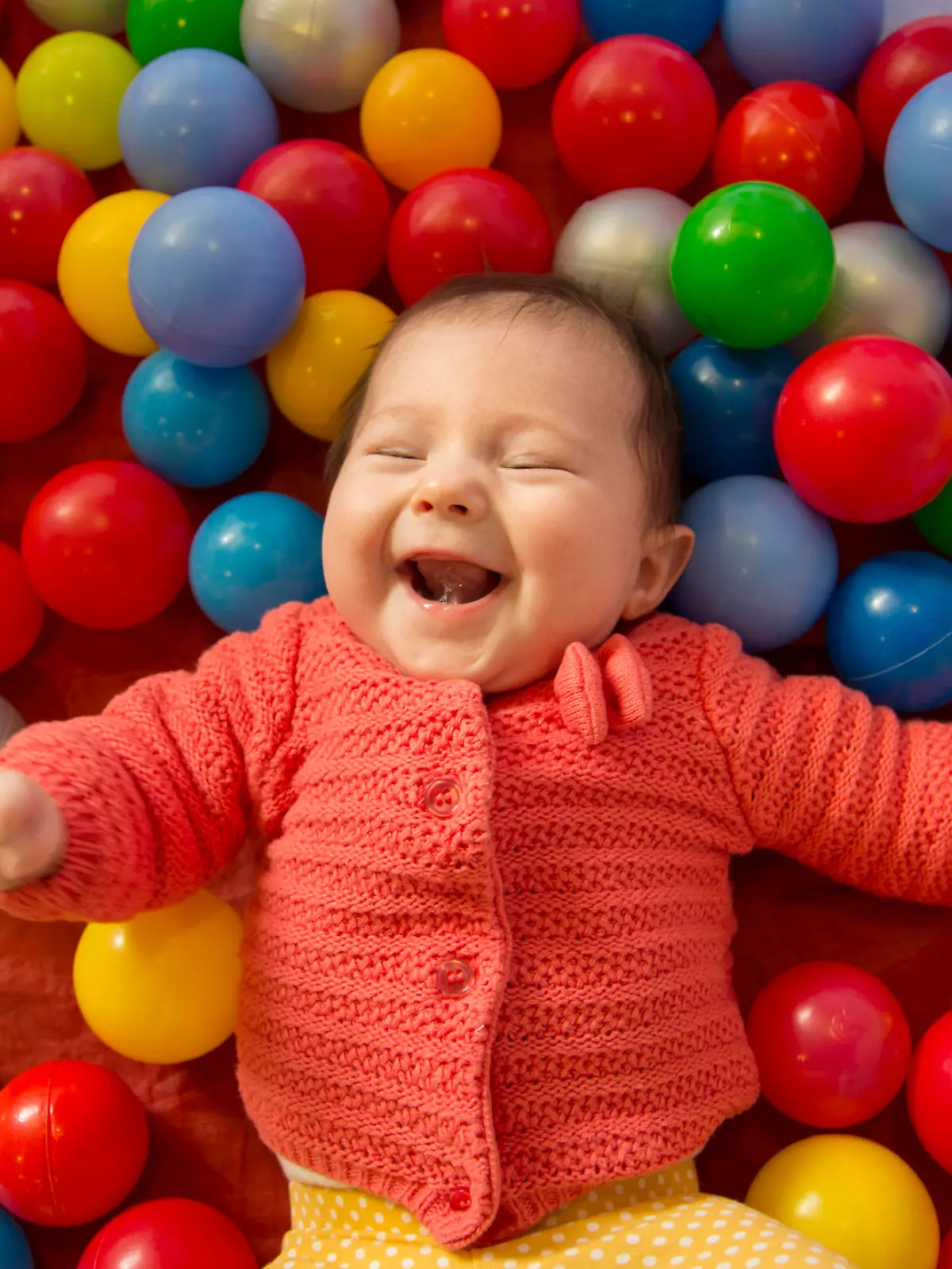 baby girl laughing in a sensory ball pit