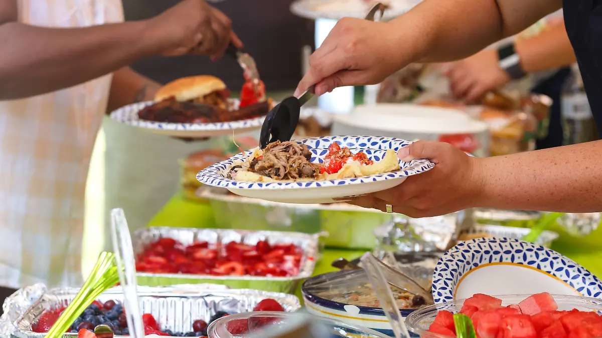 Eine Gruppe von Freunden veranstaltet einen Grillabend und bedient sich am Buffet.