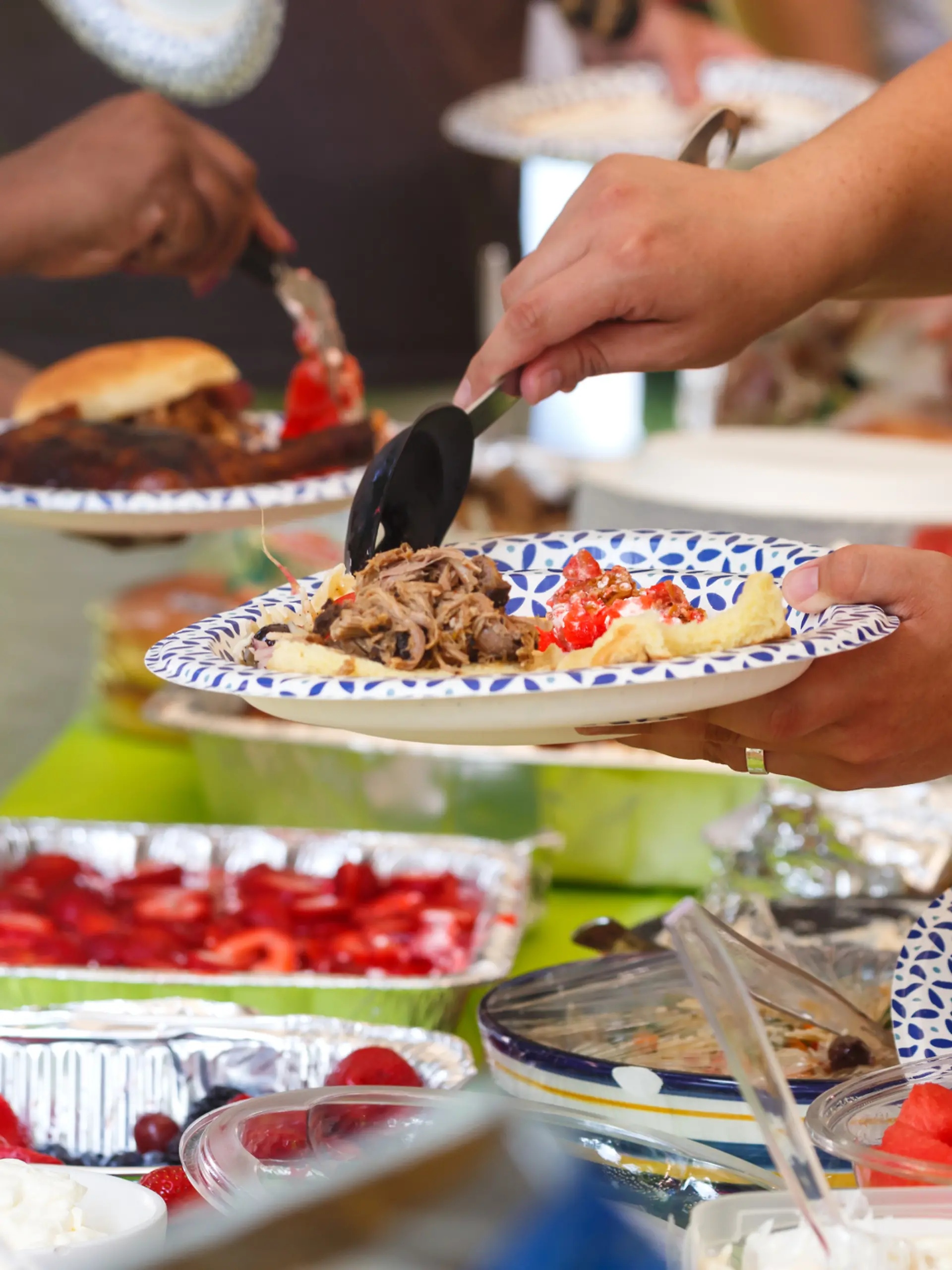 Eine Gruppe von Freunden veranstaltet einen Grillabend und bedient sich am Buffet.