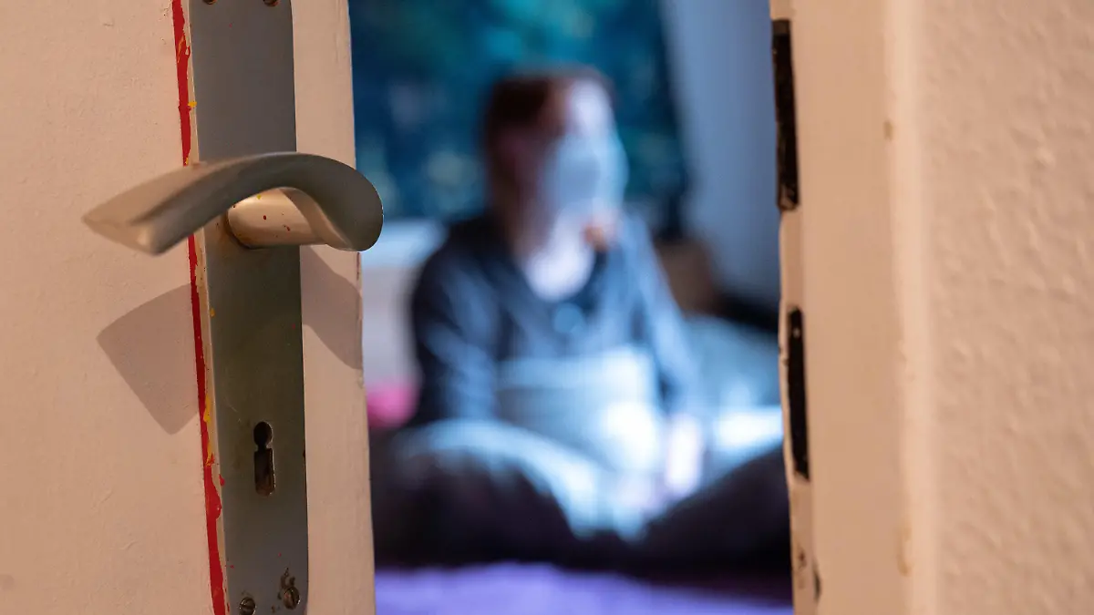 ARCHIV - 18.01.2022, Hessen, Frankfurt/Main: Eine Frau sitzt w·hrend der Isolation nach einem positiven Corona-PCR-Test auf ihrem Bett. (zu dpa: «Isolation nach Corona-Infektion wird kürzer ») Foto: Sebastian Gollnow/dpa +++ dpa-Bildfunk +++