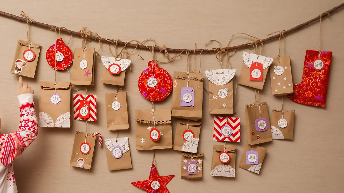 Kind steht vor einem Adventskalender an der Wand.