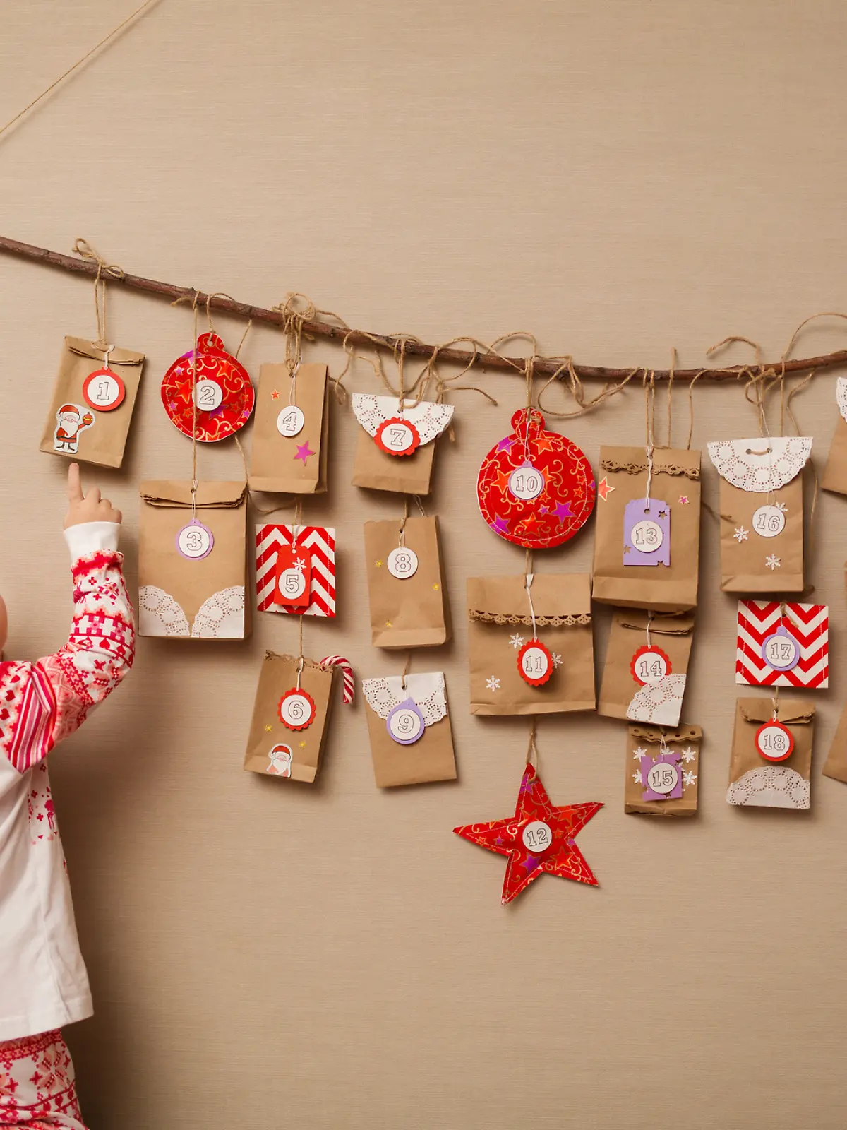 Kind steht vor einem Adventskalender an der Wand.
