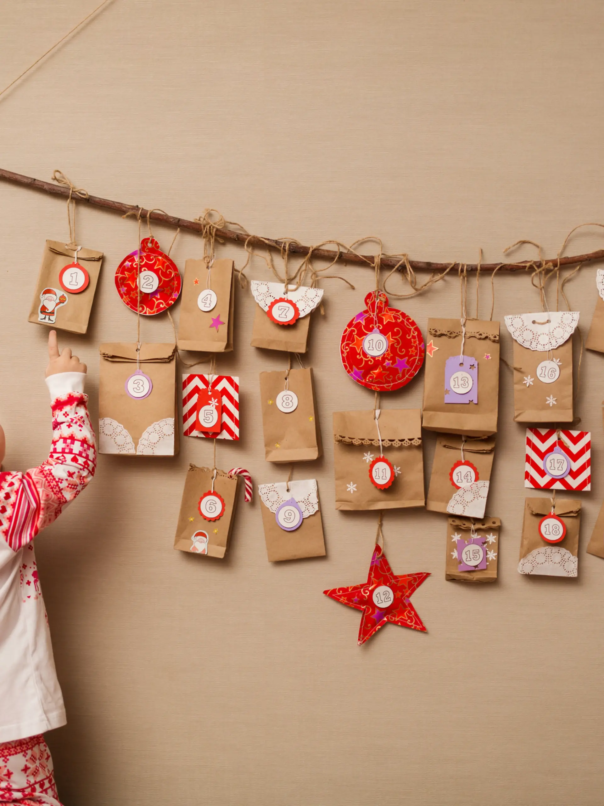 Kind steht vor einem Adventskalender an der Wand.