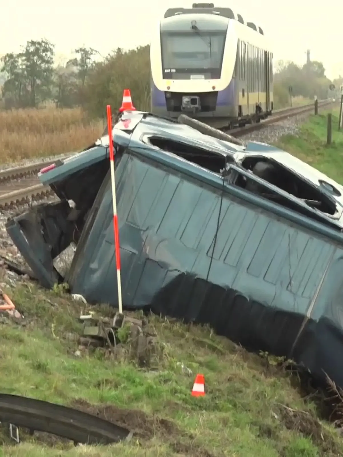 Der Nissan-Van liegt zerquetscht neben den Bahnschienen. Im Hintergrund ist der Zug zu sehen, der den Wagen gerammt hatte.
