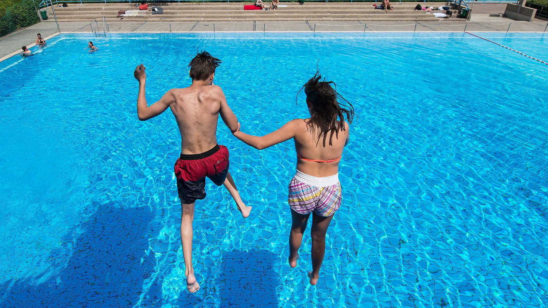 Ein Junge und ein Mädchen springen am 21.06.2017 in einem Freibad in Hannover (Niedersachsen) von einem Sprungturm ins Wasser. In Niedersachsen beginnen heute die Sommerferien. (zu dpa «Niedersachsen und Bremen starten als erste Länder in Ferien» vom 21.06.2017) Foto: Silas Stein/dpa +++(c) dpa - Bildfunk+++