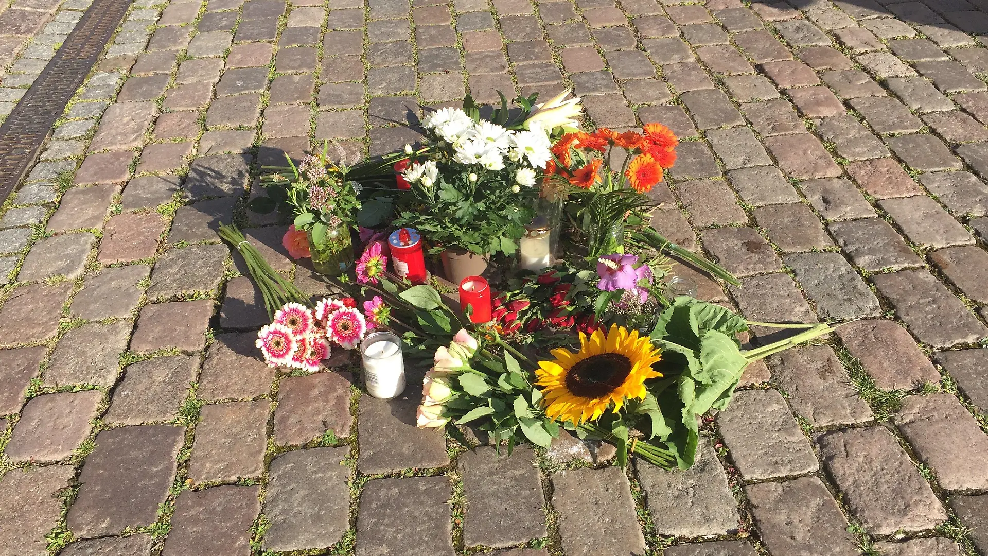 ARCHIV - 04.08.2020, Schleswig-Holstein, Kiel: Blumen liegen auf dem Platz vor dem Kieler Rathaus. Am 03.08.2020 ist eine 23-jährige Auszubildende vor dem Rathaus an ihrem ersten Ausbildungstag von einem abgebrochenen Fahnenmast erschlagen worden. Am 25. April 2022 beginnt der Prozess gegen einen Lkw-Fahrer und dessen Beifahrer wegen fahrlässiger Tötung, die den Mast zum Umstürzen gebracht hatten. Foto: Wolfgang Schmidt/dpa +++ dpa-Bildfunk +++
