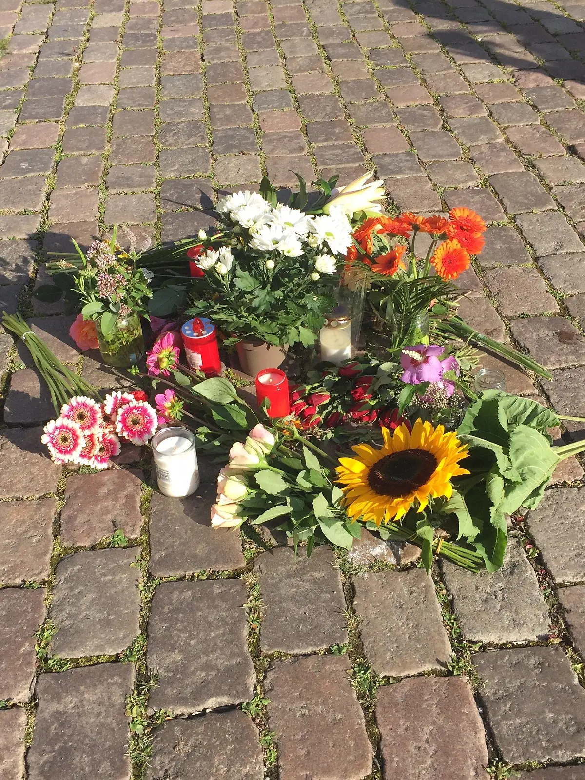 ARCHIV - 04.08.2020, Schleswig-Holstein, Kiel: Blumen liegen auf dem Platz vor dem Kieler Rathaus. Am 03.08.2020 ist eine 23-jährige Auszubildende vor dem Rathaus an ihrem ersten Ausbildungstag von einem abgebrochenen Fahnenmast erschlagen worden. Am 25. April 2022 beginnt der Prozess gegen einen Lkw-Fahrer und dessen Beifahrer wegen fahrlässiger Tötung, die den Mast zum Umstürzen gebracht hatten. Foto: Wolfgang Schmidt/dpa +++ dpa-Bildfunk +++