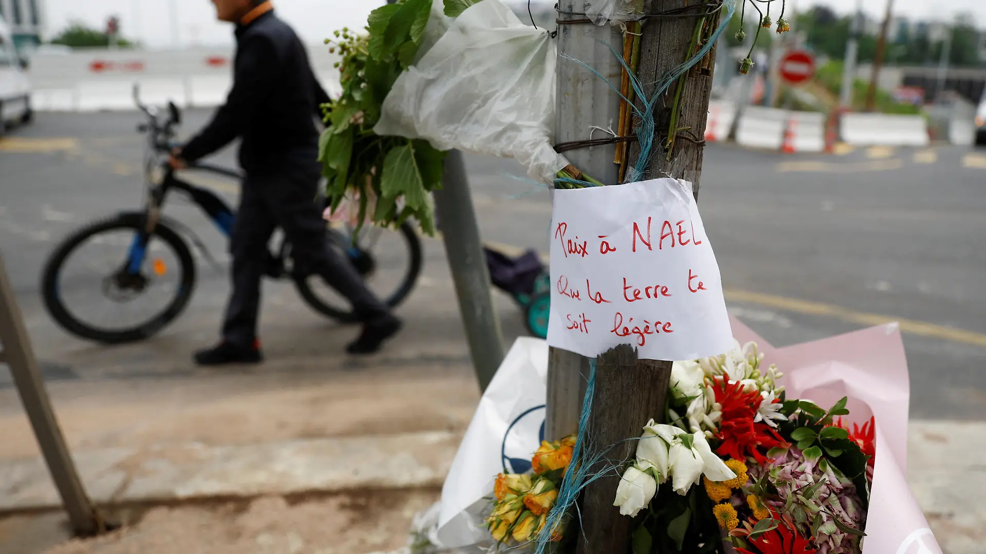Flowers are seen at the site where Nahel, a 17-year-old teenager, was killed by a French police officer during a traffic stop, in Nanterre, Paris suburb, June 29, 2023. The message reads "Peace to Nael, may the earth be light to you".  REUTERS/Gonzalo Fuentes