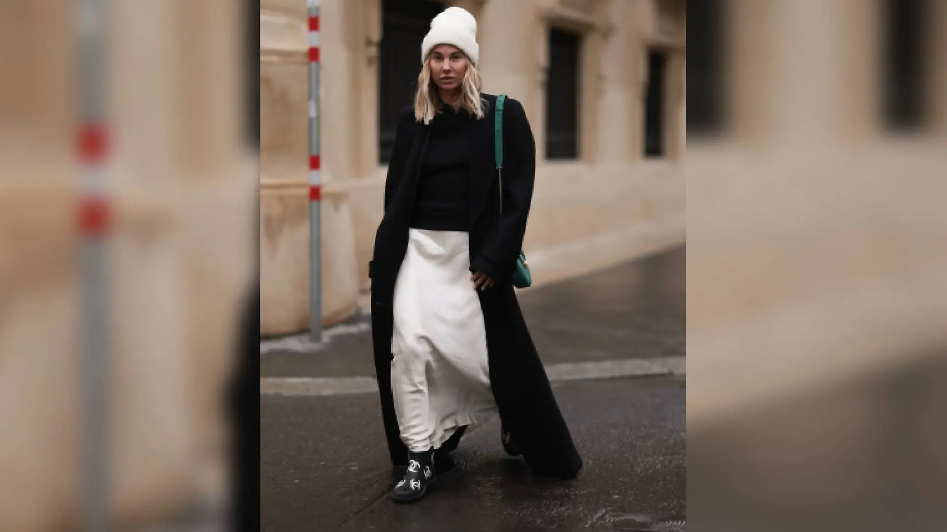 Karin Teigl trägt zu ihrem weißen Satin-Rock von Mango einen scharzen Strickpulli und einen langen schwarzen Mantel