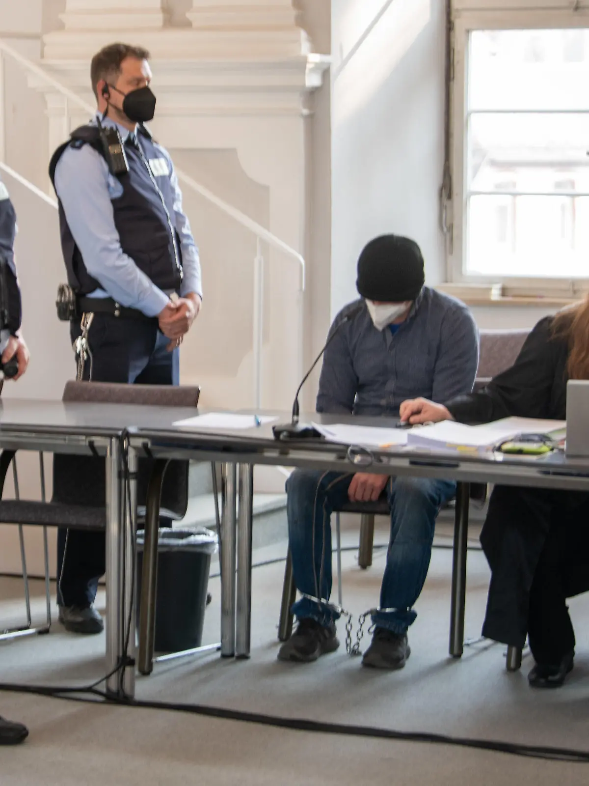 25.04.2022, Baden-Württemberg, Ellwangen: Ein Mann sitzt im Landgericht mit gesenktem Kopf auf der Anklagebank neben seinen Verteidigerinnen Sandra Ebert (l) und Sarah Schwegler. Der Mann soll das Kleinkind seiner Lebensgefährtin so schwer misshandelt zu haben, dass es starb. Foto: Stefan Puchner/dpa +++ dpa-Bildfunk +++