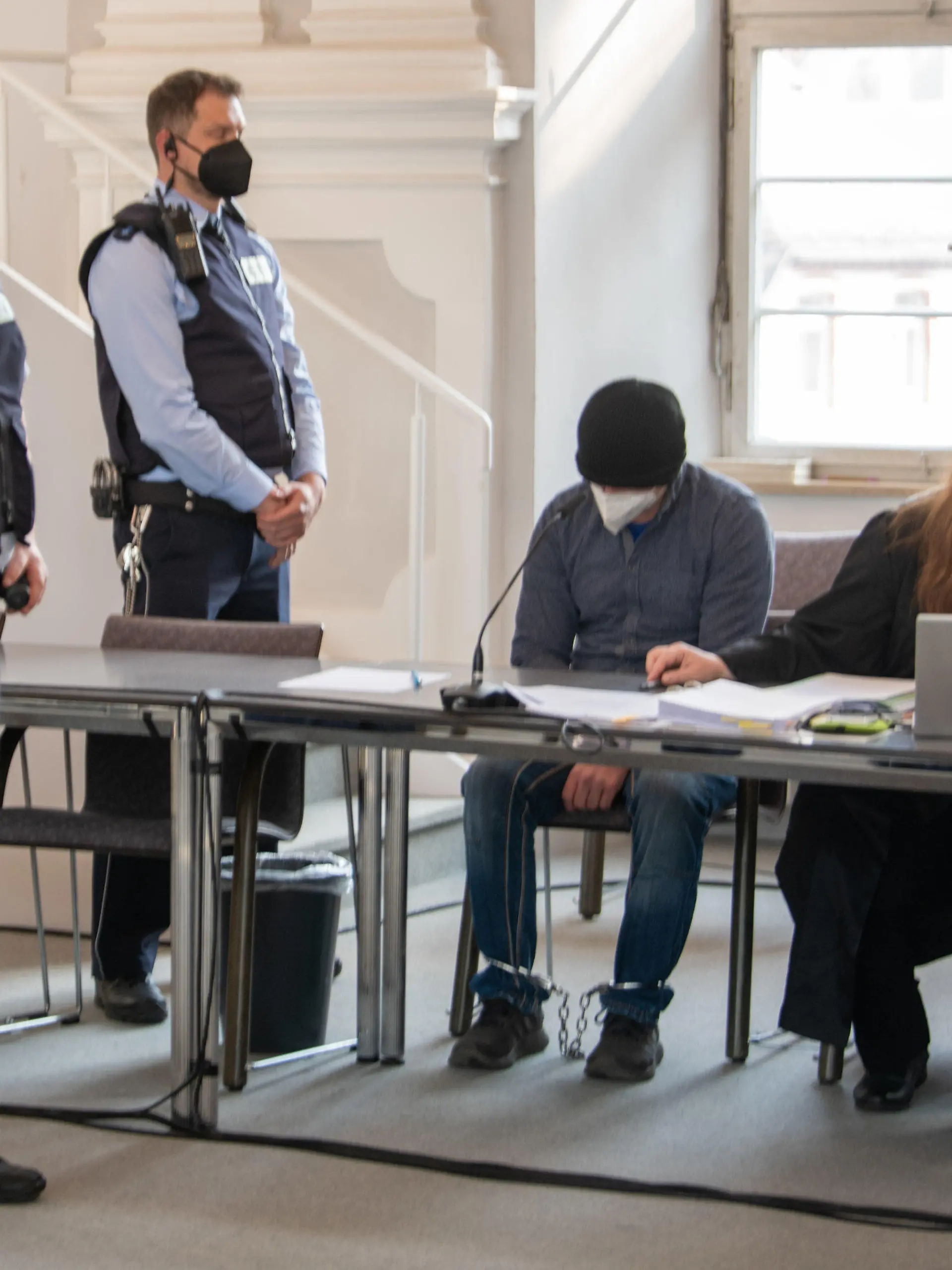 25.04.2022, Baden-Württemberg, Ellwangen: Ein Mann sitzt im Landgericht mit gesenktem Kopf auf der Anklagebank neben seinen Verteidigerinnen Sandra Ebert (l) und Sarah Schwegler. Der Mann soll das Kleinkind seiner Lebensgefährtin so schwer misshandelt zu haben, dass es starb. Foto: Stefan Puchner/dpa +++ dpa-Bildfunk +++