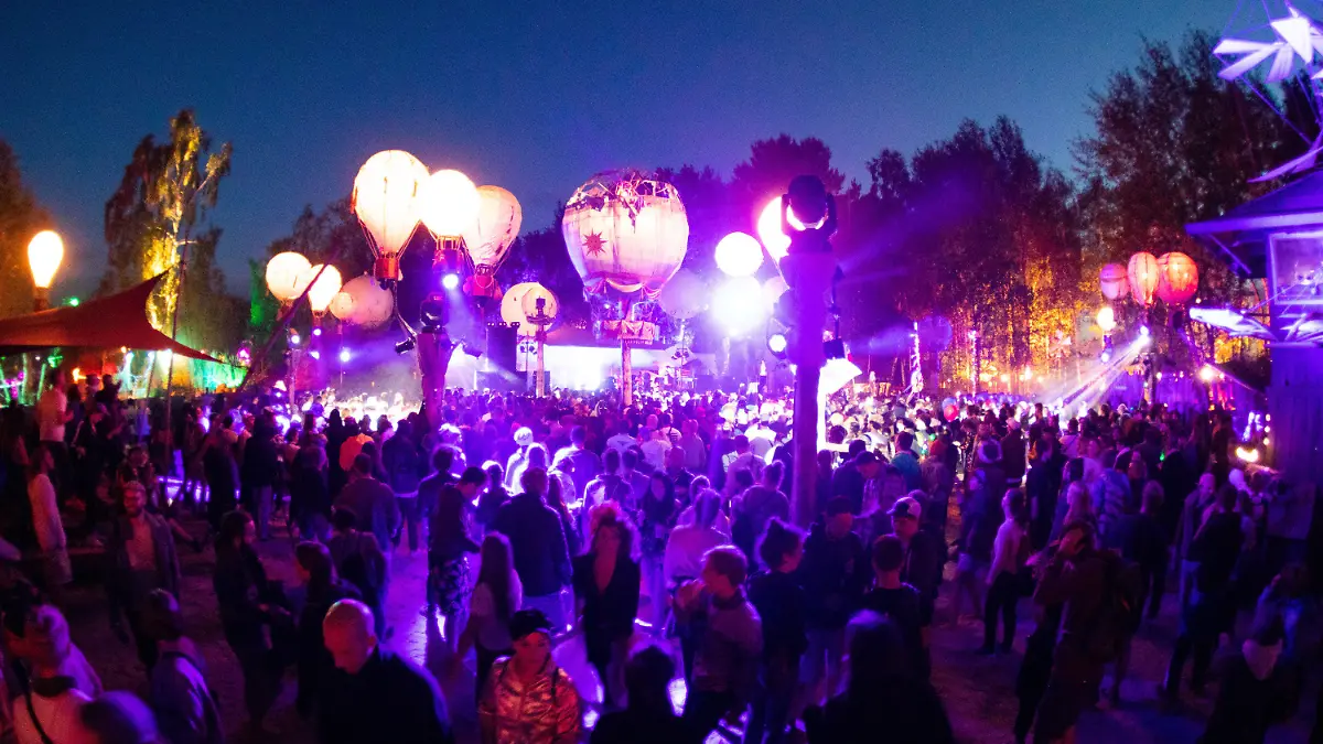 ARCHIV - 27.06.2019, Mecklenburg-Vorpommern, Lärz: Festivalbesucher tanzen auf einer mit leuchtenden Ballonen geschmückten Bühne auf dem Gelände des Fusion-Festival. In einer Woche soll in Lärz das Fusion-Festival 2023 beginnen. Die Veranstalter erwarten wieder mehrere zehntausend Gäste - und warnen vor Betrügern. (zu dpa "Fusion-Veranstalter warnen vor Betrug - 70 000 Gäste erwartet") Foto: Christian Charisius/dpa +++ dpa-Bildfunk +++