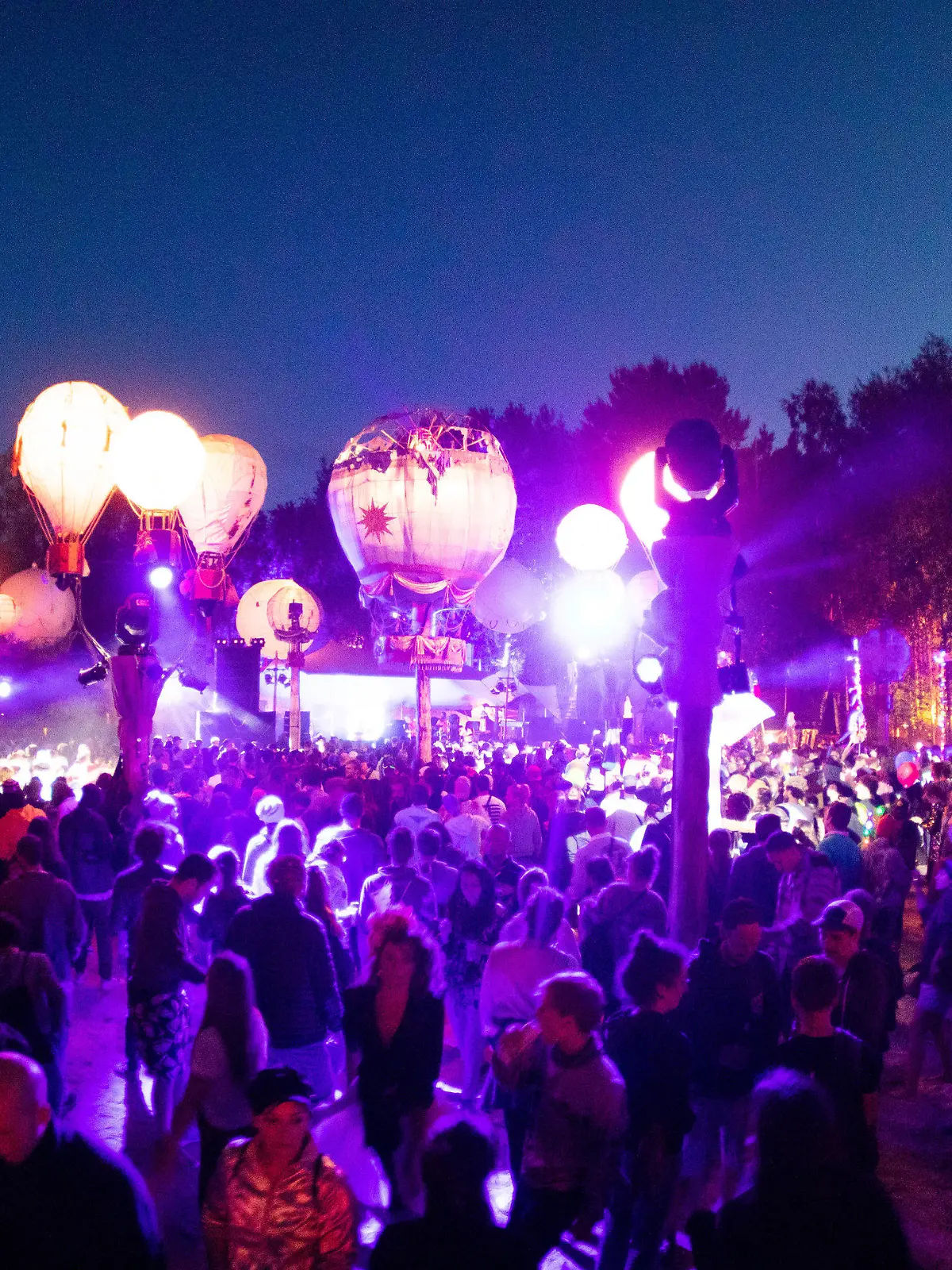 ARCHIV - 27.06.2019, Mecklenburg-Vorpommern, Lärz: Festivalbesucher tanzen auf einer mit leuchtenden Ballonen geschmückten Bühne auf dem Gelände des Fusion-Festival. In einer Woche soll in Lärz das Fusion-Festival 2023 beginnen. Die Veranstalter erwarten wieder mehrere zehntausend Gäste - und warnen vor Betrügern. (zu dpa "Fusion-Veranstalter warnen vor Betrug - 70 000 Gäste erwartet") Foto: Christian Charisius/dpa +++ dpa-Bildfunk +++
