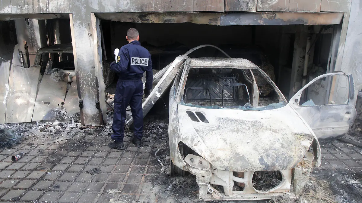 A police officer watches a charred car at the town hall of Mons-en-Barœul, northern France Thursday, June 29, 2023. Protesters angry after police shot a 17-year-old boy dead set cars and buildings ablaze in Paris suburbs. Unrest spread to some other French cities and towns Wednesday night and Thursday morning, despite increased security efforts and the president's calls for calm. (AP Photo/Michel Spingler)