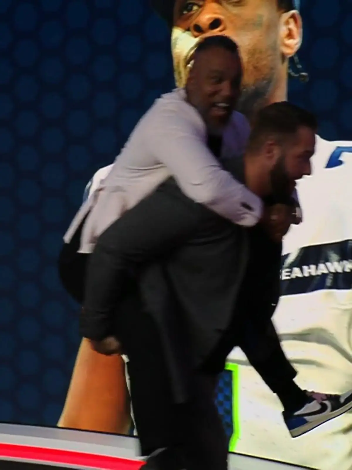 Bild zu: "Coach Esume und Björn Werner rennen huckepack durchs Studio "