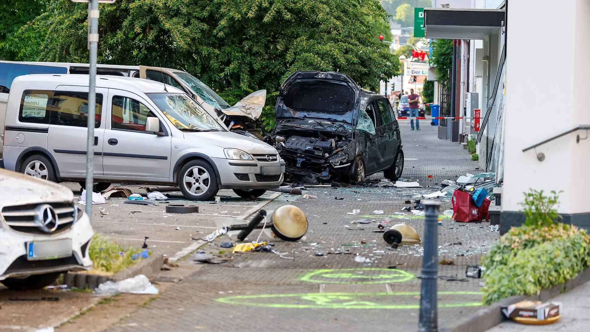 28.06.2023, Rheinland-Pfalz, Neuwied: Kaputte Autos stehen an der Unfallstelle, hinten rechts das Fahrzeug der Unfallverursacherin. In einer verkehrsberuhigten Zone hat es einen schweren Unfall gegeben. Dabei wurden nach ersten Informationen der Polizei vier Menschen schwer verletzt, zwei weitere erlitten leichte Verletzungen. Eine Frau war mit ihrem Fahrzeug nach jetzigem Stand der Ermittlungen von der Fahrbahn abgekommen und gegen Autos gefahren. Schließlich sei sie mit ihrem Auto in ein Schaufenster «gerutscht» und zum Stillstand gekommen, sagte ein Sprecher der Polizei. Die Frau wurde dabei schwer verletzt. Foto: Jörg Halisch/dpa - ACHTUNG: Autokennzeichen aus rechtlichen Gründen gepixelt +++ dpa-Bildfunk +++