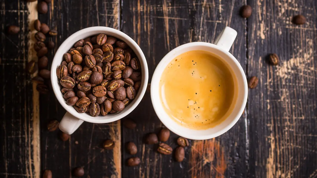 Fresh espresso and whole roaster coffee beans in a white cups on old dark wooden textured table