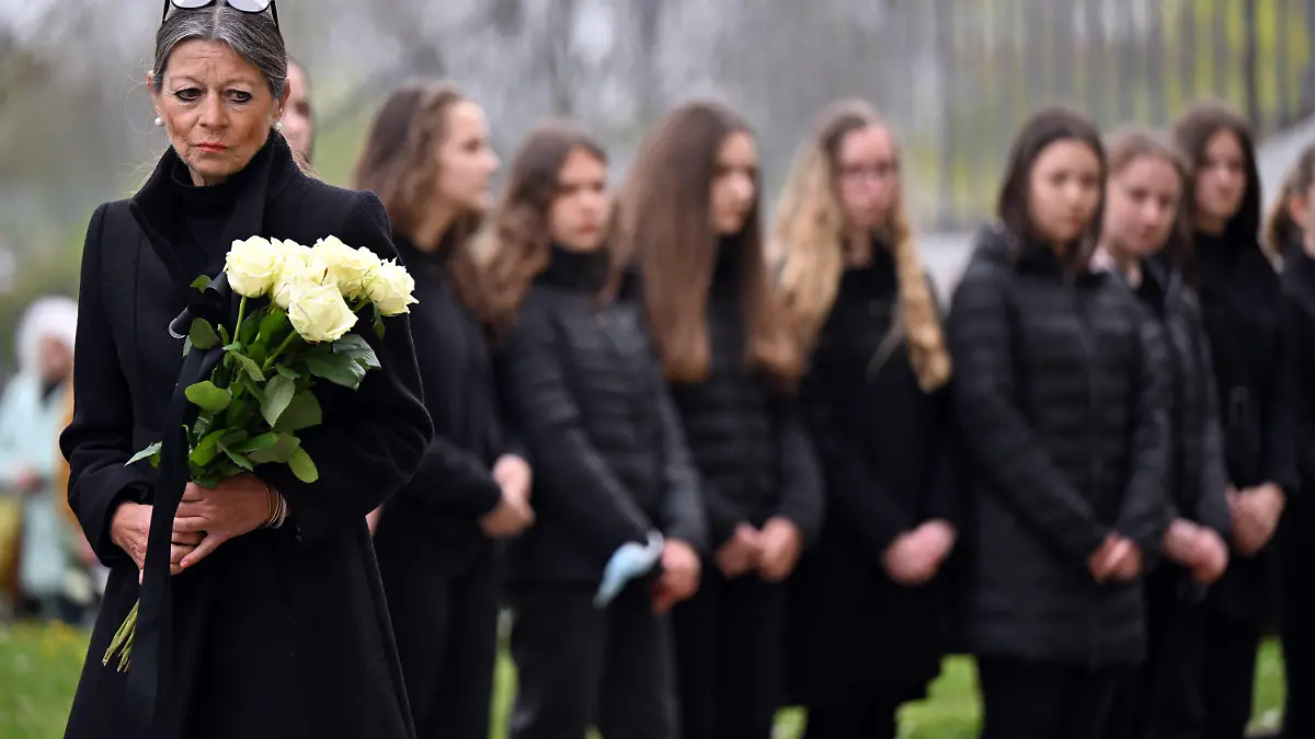 26.04.2022, Thüringen, Erfurt: Christiane Alt, Schulleiterin, hält weiße Rosen in den Händen am Gutenberg-Gymnasium 20 Jahre nach dem Amoklauf. Am 26. April 2002 erschießt ein ehemaliger Schüler am Gutenberg-Gymnasium 16 Menschen und tötet sich anschließend selbst. Am 20. Jahrestag versammeln sich an den Stufen der sanierten Schule Schülerinnen und Schüler, Angehörige der Opfer und Erfurter, die sie kannten sowie ehemaligen Lehrkräfte und Schüler zum Gedenken. Foto: Martin Schutt/dpa +++ dpa-Bildfunk +++