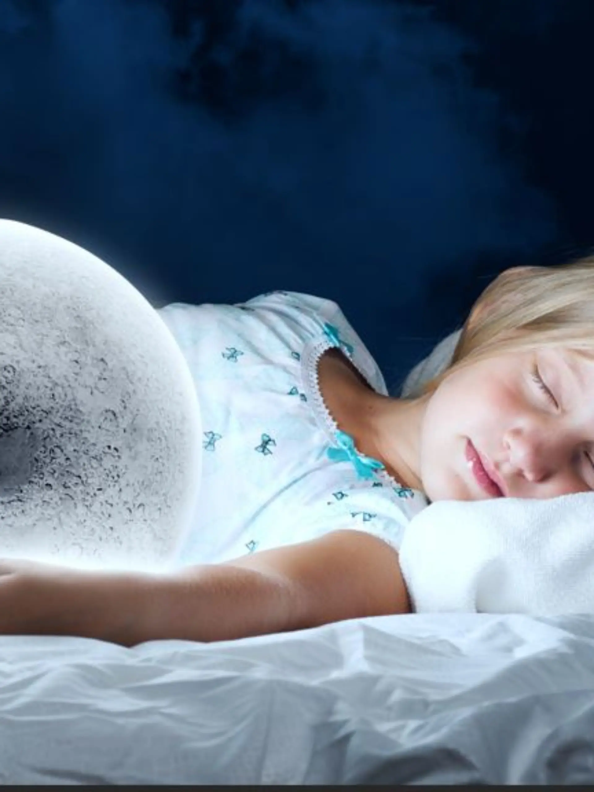 Kind liegt mit geschlossenen Augen im Bett und hat die Hand an einem leuchtenden LED-Licht in Globusform.