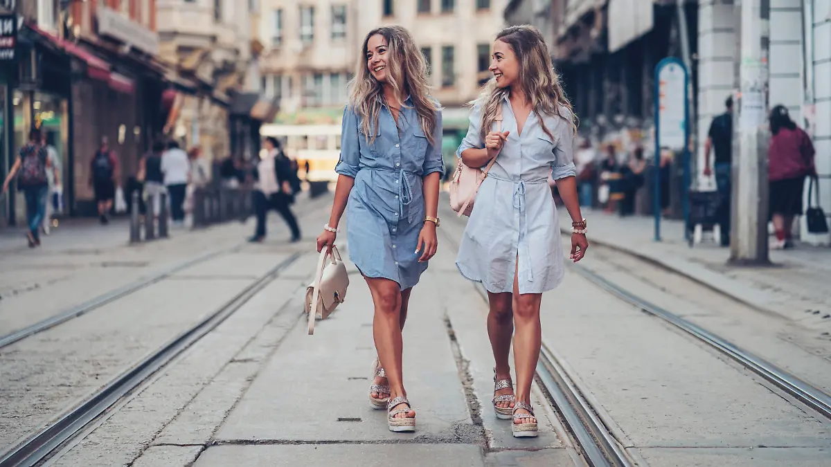 Smiling twin sisters walking on the street