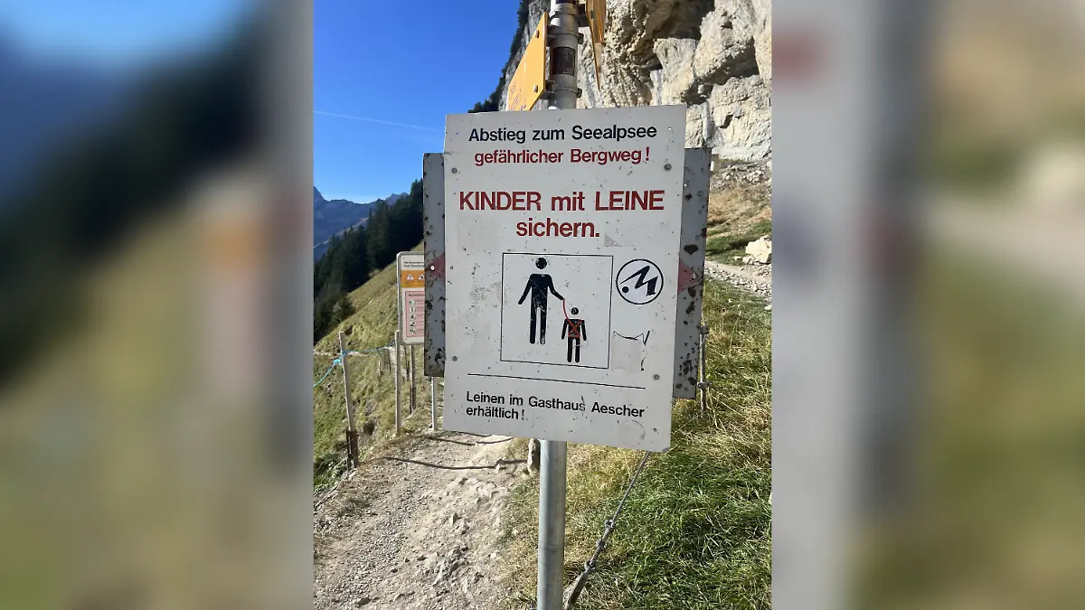 Ein Schild in den Schweizer Alpen fordert Eltern auf, ihre Kinder an der Leine zu führen.