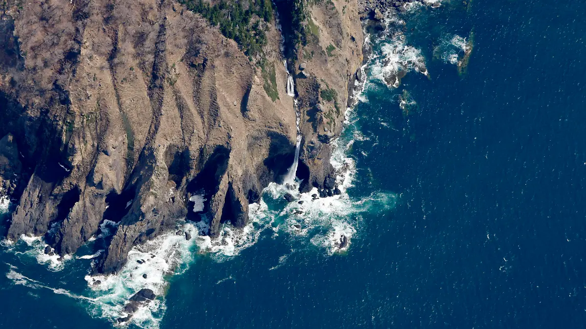ADDS THE KASHUNI WATERFALL - This aerial photo shows the Kashuni Waterfall, seen at center, near the waters where rescuers continue search for the passengers on a missing tour boat, off Shiretoko Peninsula, Hokkaido, northern Japan Sunday, April 24, 2022. The Japanese Coast Guard said Sunday that rescue helicopters found several of the 26 people from a tour boat missing in the frigid waters of northern Japan since the day before. The location, near the Kashuni Waterfall, is known as a difficult place to maneuver boats because of its rocky coastline and strong tide.(Masanori Takei/Kyodo News via AP)