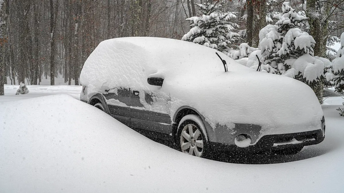 A car covered by snow under snowfall
