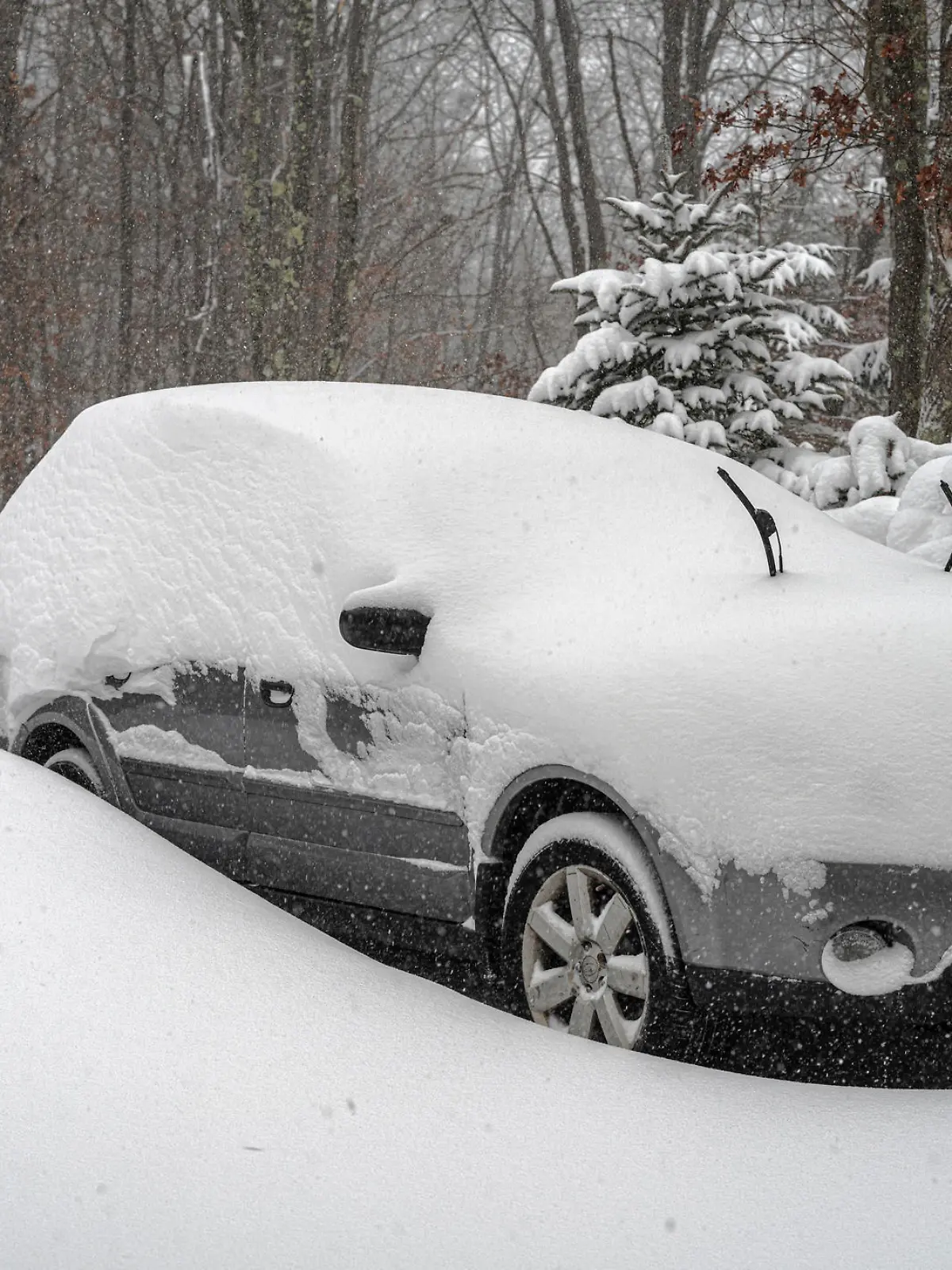 A car covered by snow under snowfall